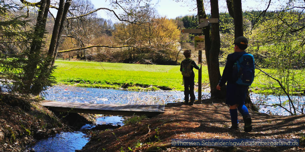 Zwei Kinder spielen im Wald am Fluss